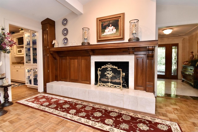 living room featuring parquet flooring, lofted ceiling with beams, and a tile fireplace