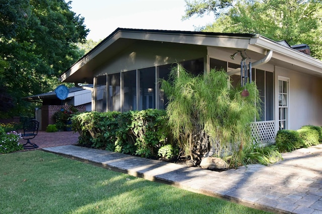 view of side of home featuring a sunroom and a lawn