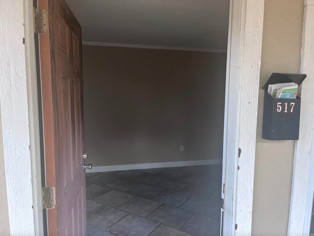 hall with ornamental molding and dark tile patterned flooring