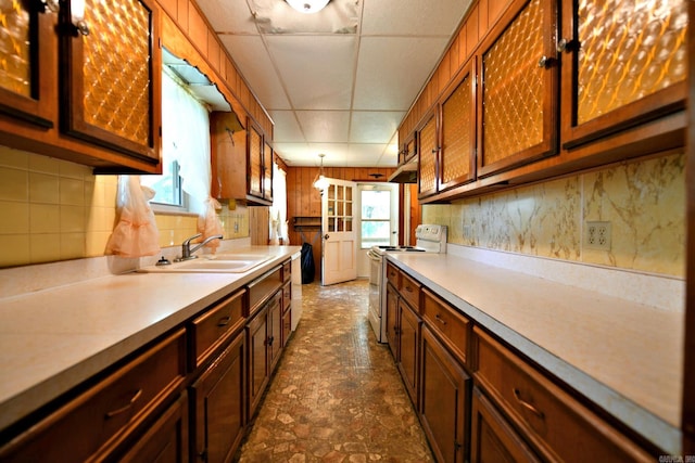 kitchen featuring a drop ceiling, white electric stove, hanging light fixtures, dark tile patterned flooring, and sink