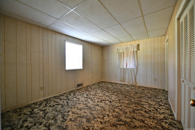 unfurnished bedroom with carpet, a closet, and a drop ceiling