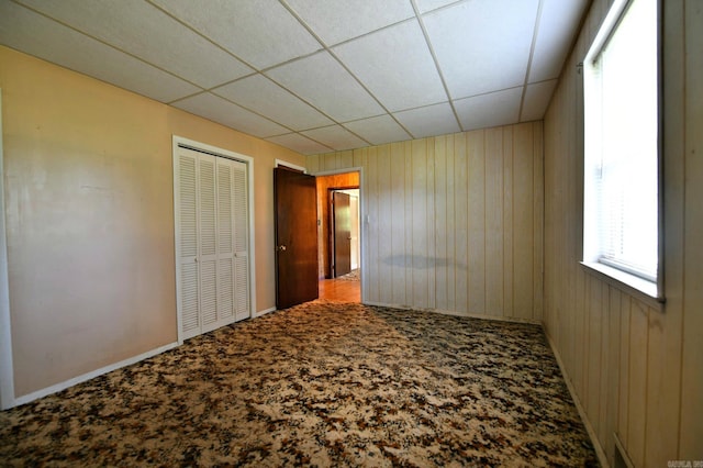 unfurnished bedroom featuring carpet, a closet, and a paneled ceiling