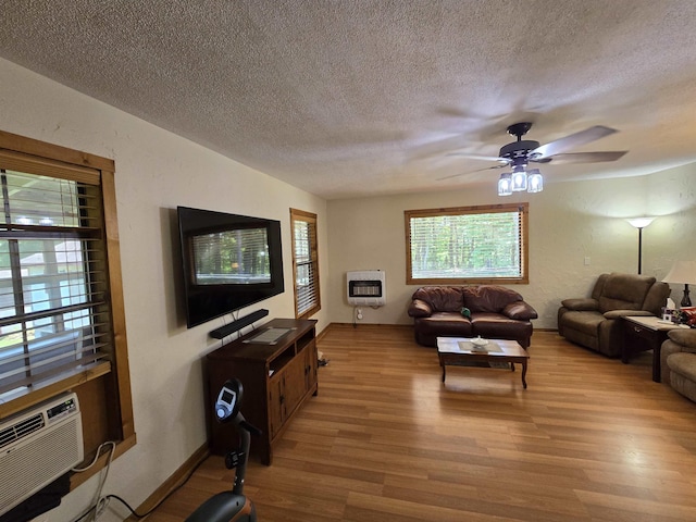 living room featuring ceiling fan, heating unit, a textured ceiling, and light hardwood / wood-style floors