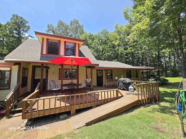 rear view of house with a wooden deck and a lawn