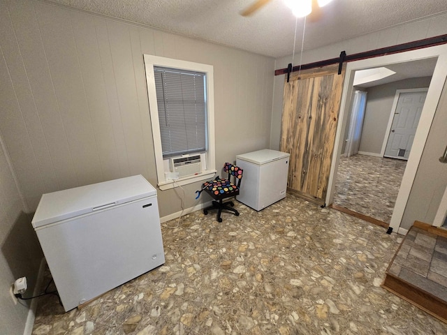 laundry area featuring a textured ceiling, wooden walls, cooling unit, ceiling fan, and a barn door