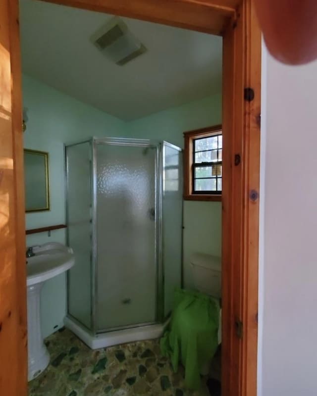 bathroom with toilet and a shower with door