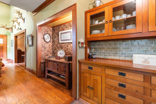 interior space with tasteful backsplash, ornamental molding, and light hardwood / wood-style floors