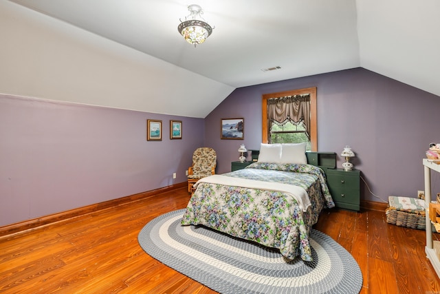 bedroom with vaulted ceiling and hardwood / wood-style flooring