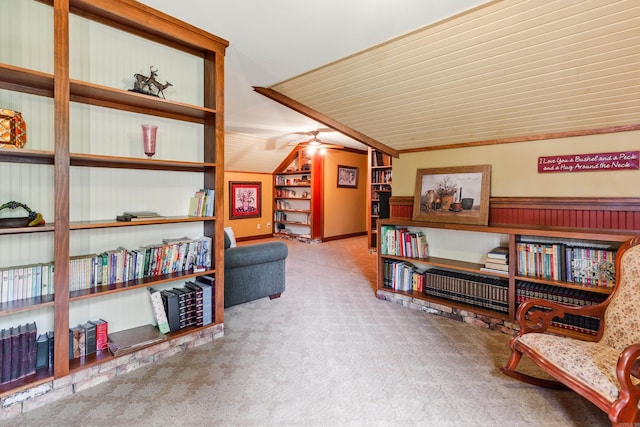 sitting room with carpet, vaulted ceiling, ceiling fan, and ornamental molding