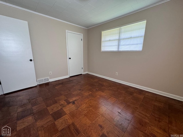 spare room featuring ornamental molding and dark parquet floors