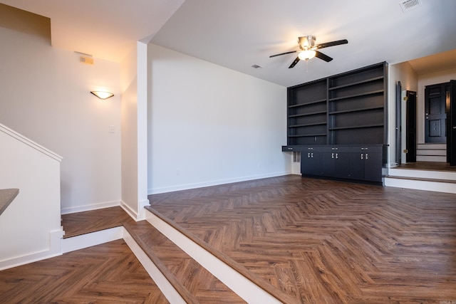 unfurnished living room with ceiling fan and dark parquet floors