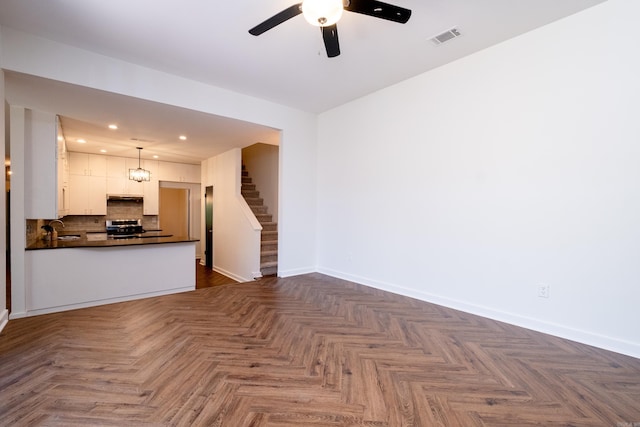 unfurnished living room featuring ceiling fan, sink, and dark parquet floors