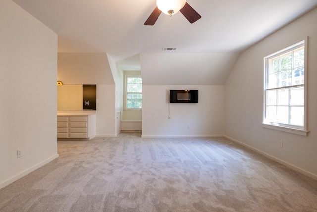 unfurnished living room with light colored carpet, vaulted ceiling, and a wealth of natural light