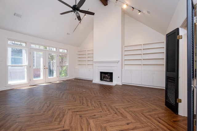 unfurnished living room featuring built in features, high vaulted ceiling, dark parquet flooring, a fireplace, and french doors