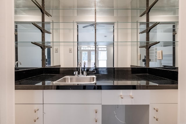 kitchen with white cabinetry, dark stone counters, and sink