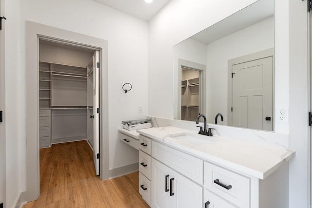 bathroom with a spacious closet, wood finished floors, and vanity