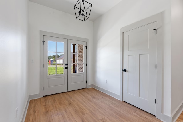 entryway featuring a notable chandelier, french doors, light wood-style flooring, and baseboards