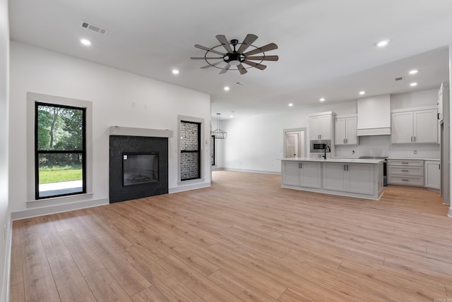 kitchen featuring stainless steel appliances, visible vents, a high end fireplace, open floor plan, and premium range hood