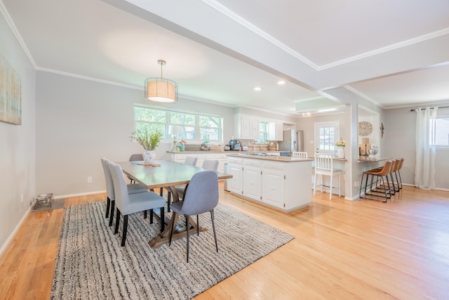 dining area with ornamental molding, light hardwood / wood-style flooring, and a healthy amount of sunlight