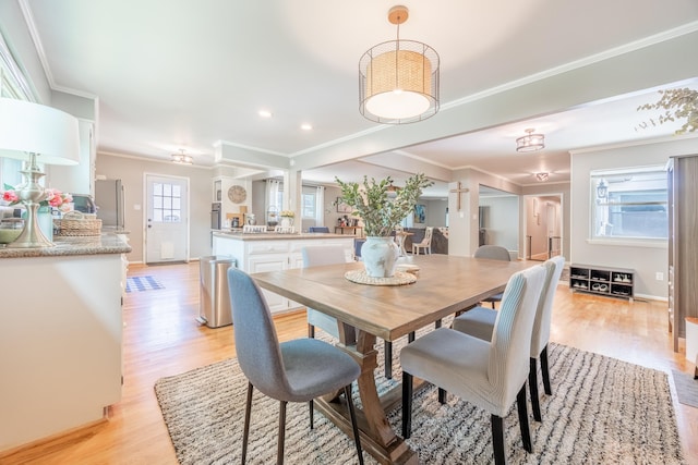 dining area with a wealth of natural light, crown molding, and light wood-type flooring