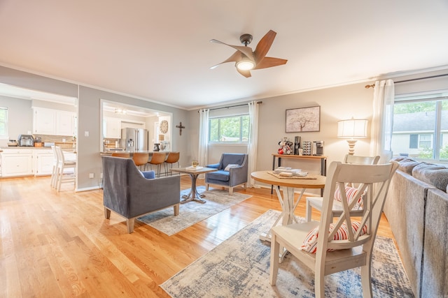 living room with ceiling fan, crown molding, and light hardwood / wood-style flooring