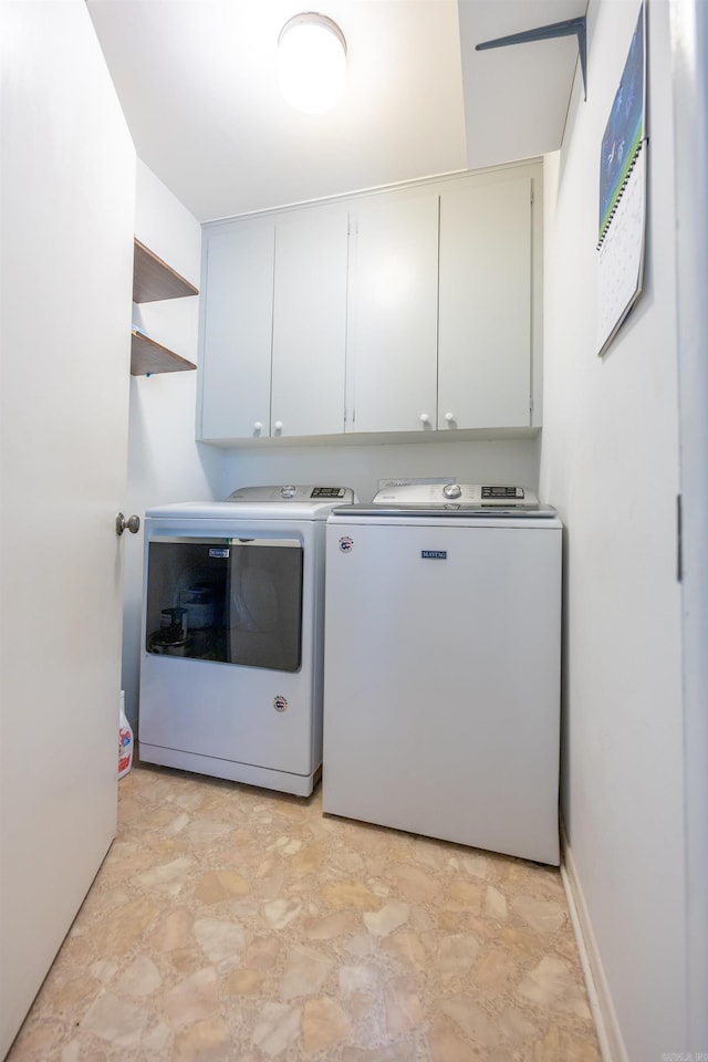 laundry room featuring cabinets, light tile patterned flooring, and washer and clothes dryer