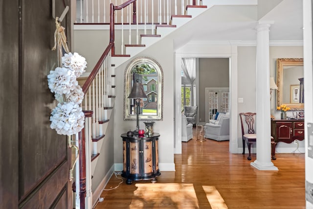 foyer with ornamental molding, decorative columns, and wood-type flooring