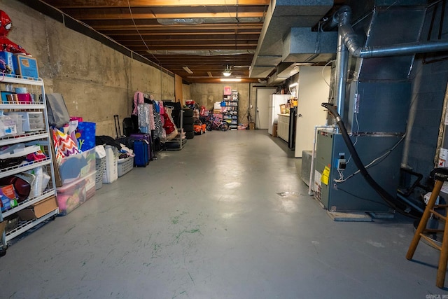 basement featuring white refrigerator and heating unit