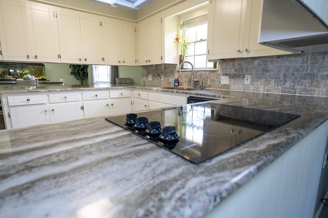 kitchen featuring sink, white cabinetry, tasteful backsplash, range hood, and black appliances