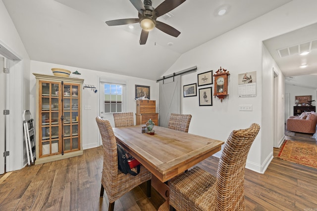 dining space featuring vaulted ceiling, a barn door, ceiling fan, and dark hardwood / wood-style floors