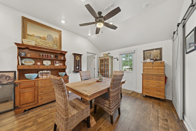 dining area featuring dark hardwood / wood-style floors, ceiling fan, lofted ceiling, and a barn door