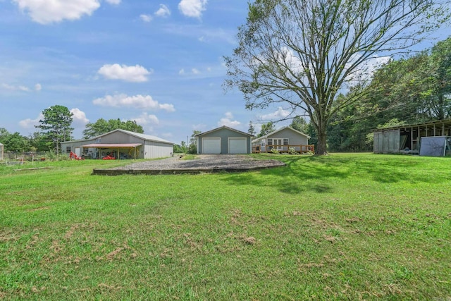 view of yard featuring a garage, a carport, and an outdoor structure