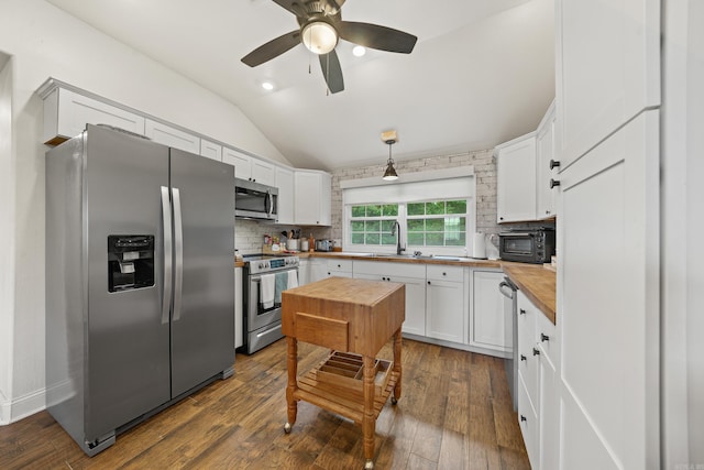 kitchen with hanging light fixtures, dark wood-type flooring, butcher block countertops, and stainless steel appliances