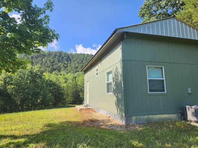 view of side of home with central AC unit and a lawn