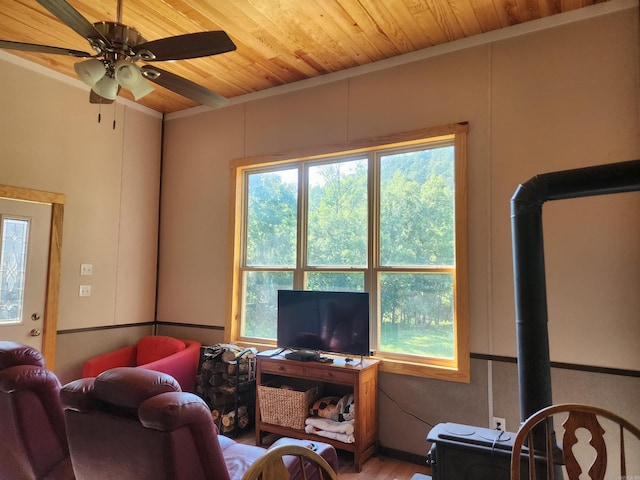 living room featuring hardwood / wood-style flooring, a wood stove, wood ceiling, crown molding, and ceiling fan