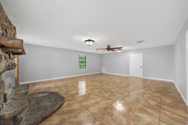 living room featuring light tile patterned floors, a stone fireplace, and ceiling fan