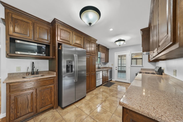 kitchen with sink, light tile patterned floors, light stone counters, and stainless steel appliances