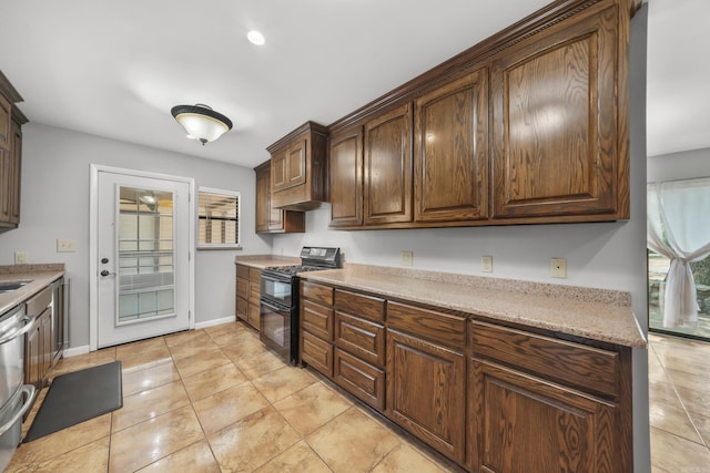 kitchen with black range with gas stovetop, light tile patterned floors, light stone counters, and dark brown cabinetry