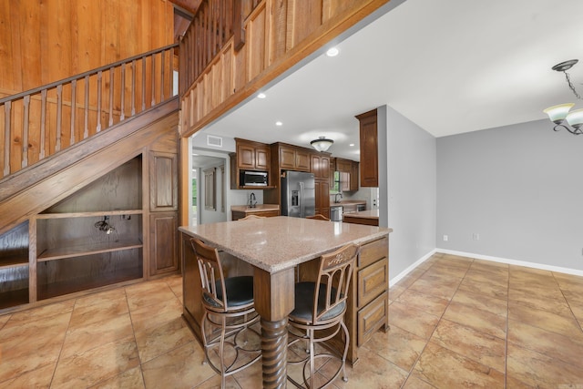 kitchen with a center island, light stone counters, stainless steel appliances, and light tile patterned floors