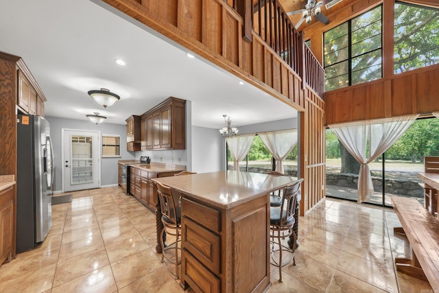 kitchen with light tile patterned flooring, electric stove, a center island, a breakfast bar area, and stainless steel fridge