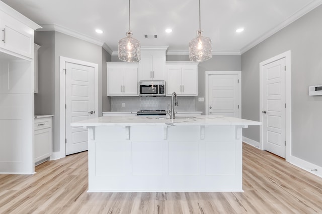 kitchen featuring white cabinetry, sink, decorative light fixtures, and a center island with sink