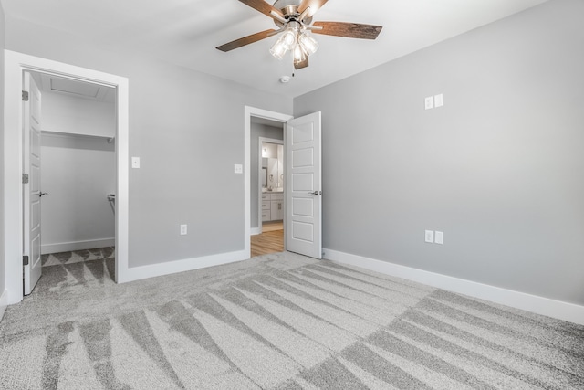 unfurnished bedroom with ceiling fan, light colored carpet, a closet, and a walk in closet