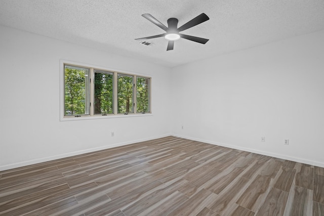 empty room with ceiling fan, wood-type flooring, and a textured ceiling