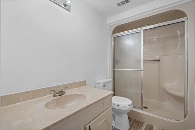 bathroom with hardwood / wood-style floors, vanity, walk in shower, a textured ceiling, and toilet