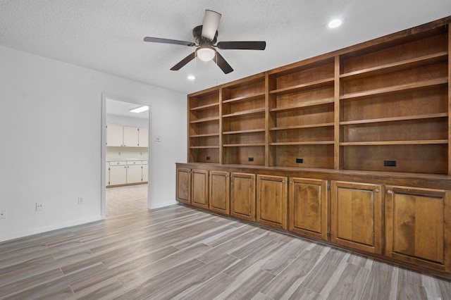 interior space featuring a textured ceiling, ceiling fan, and light hardwood / wood-style flooring