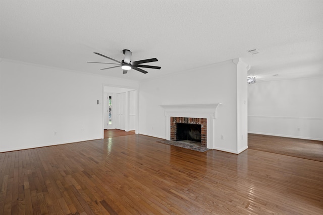 unfurnished living room with a fireplace, dark hardwood / wood-style flooring, ornamental molding, ceiling fan, and a textured ceiling