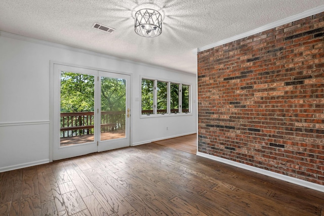 spare room with ornamental molding, brick wall, a textured ceiling, and hardwood / wood-style floors