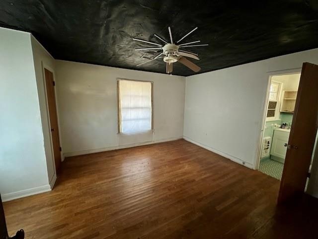 unfurnished bedroom with ceiling fan, ensuite bath, and wood-type flooring