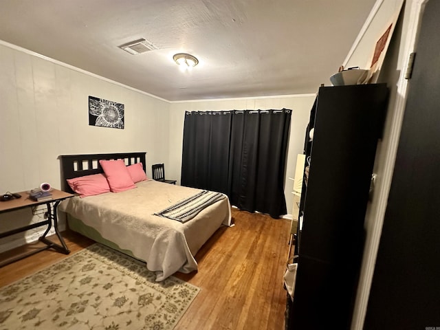 bedroom with light hardwood / wood-style floors and ornamental molding