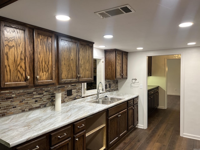 kitchen with dark hardwood / wood-style flooring, sink, backsplash, and dark brown cabinetry